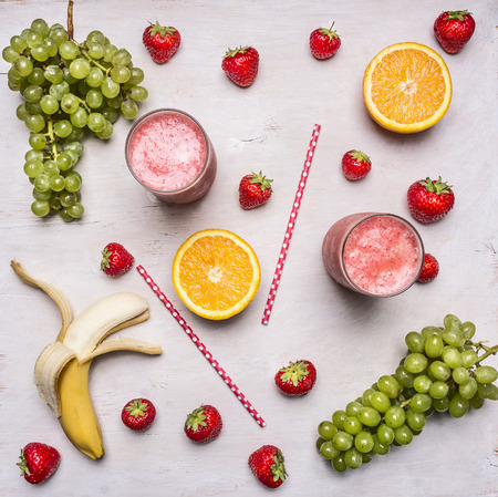 Superfoods and health or detox diet food concept. Fresh organic Smoothie ingredients.Assortment of fruit and vegetables smoothies in glass with straws on white wooden backgroundの写真素材