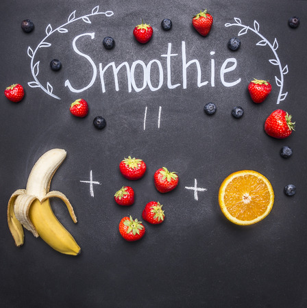 Superfoods and health or detox diet food concept cooking smoothie with bananas and strawberries, on the chalk board, top viewの写真素材