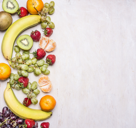 Delicious assortment of fresh fruit  laid out in a border on a white rustic background top view Superfoods and health or detox diet food concept.の写真素材