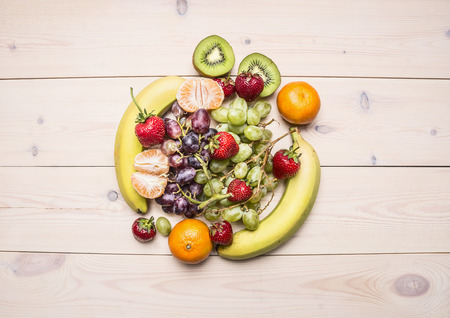 Healthy lifestyle background with various colorful fruit, laid out in the center of the white wooden table top viewの写真素材