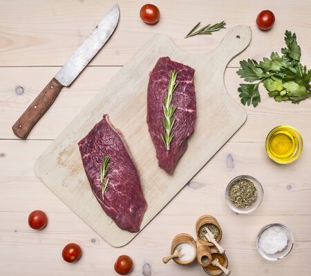 raw meat on a cutting board with a knife for meat and herbs on wooden rustic background top view close upの写真素材