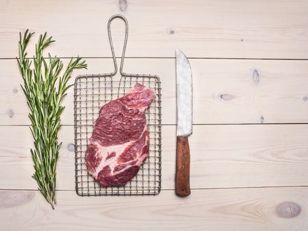 raw pork steak on the grill for cooking meat with a knife and rosemary border ,place for textの写真素材