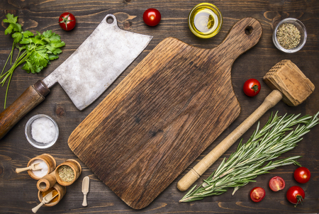 old cutting board with spices and herbs for cooking meat with cherry tomatoes and meat ax place for text, frameの写真素材