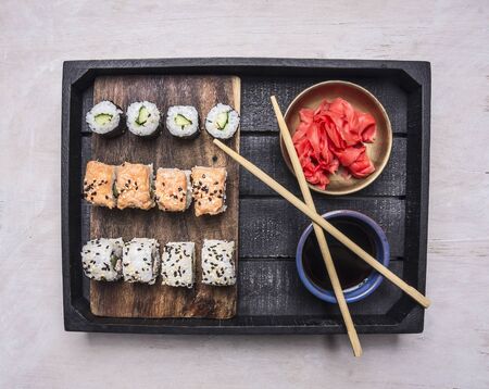 Japanese fast food, sushi set in a wooden tray with soy sauce and ginger , Asian cuisine on wooden rustic background top view close upの写真素材