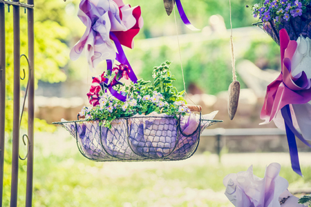 handmade flowerbed with beautiful colored flowers inside, standing on the lawn in the park on a background of blurred natural landscape and the sunlight, sunny summer dayの写真素材