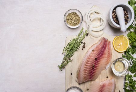 raw fillet of tilapia with salt, lemon and butter, rosemary and herbs, border place for textの写真素材