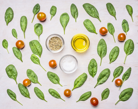 Healthy foods, cooking and vegetarian concept fresh spinach leaves are laid out around the condiments and oil, top view, on a rustic wooden backgroundの写真素材