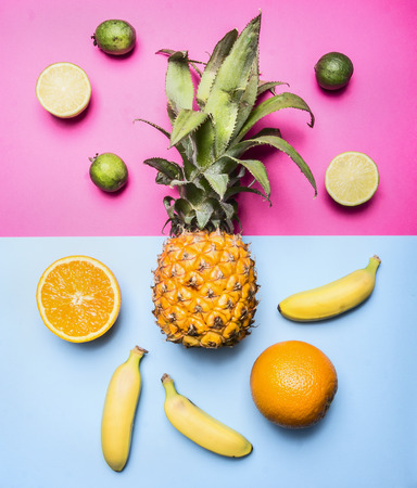 concept of summer fruit set against a bright background mini pineapple, mango, mini bananas, carambola, lime, quince, top viewの写真素材
