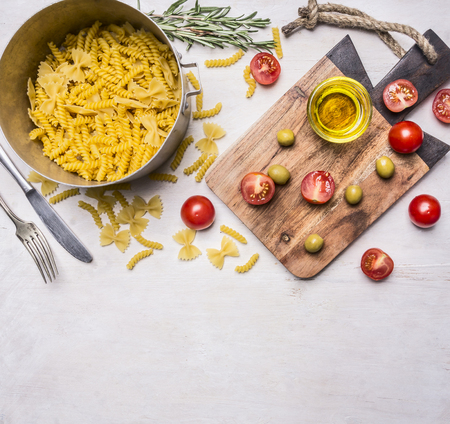 cooking vegetarian pasta with herbs and cherry tomatoes on a cutting board, pasta laid out on a wooden rustic background, Border, place for textの写真素材