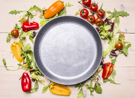 Healthy foods, cooking and vegetarian concept Various vegetables laid out around a metal pan, frame, space for textの写真素材