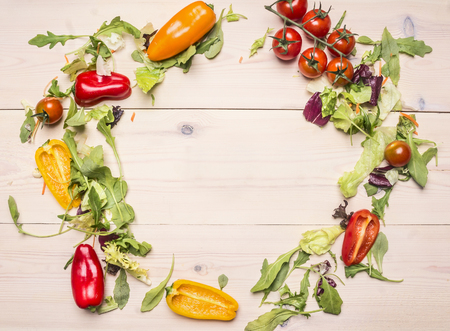 Superfoods and health or detox diet food concept various vegetables and herbs lined frame on a white wooden table, cherry tomatoes, bell peppers, arugula, space for textの写真素材