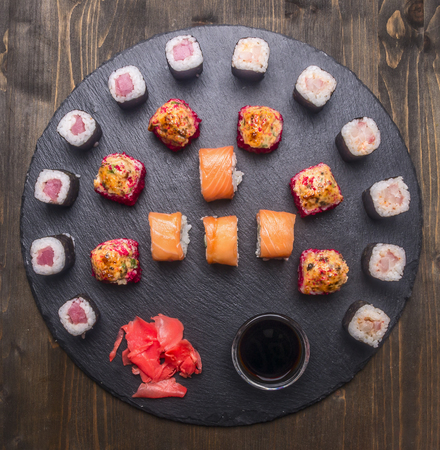 Japanese food, sushi with salmon and tuna, Philadelphia roll, and baked sushi, fresh ginger and chopsticks, soy sauce, laid out on a tray of chalk boards, frame, space for text, top viewの写真素材