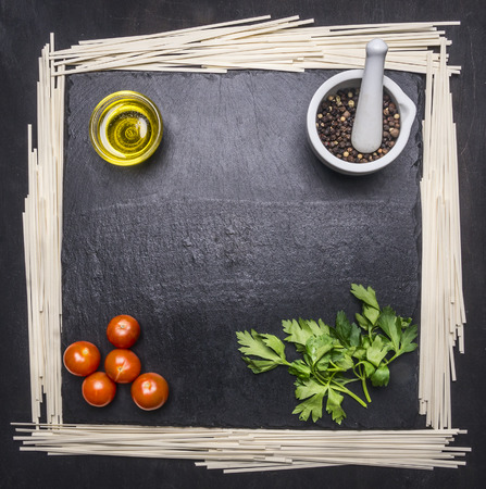 noodles with tomatoes and oranges on a cutting board with herbs, frame space for textの写真素材