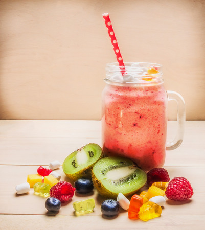 Fruit smoothies with berries on white wooden table, near a variety of ingredients laid out, close upの写真素材