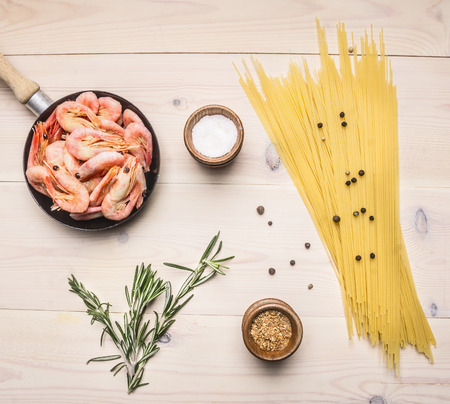 concept cooking pasta with shrimp with spices, herbs and pepper in a small pan, Asian food Asian food on wood white background top viewの写真素材