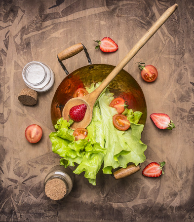 ingredients vegetarian salad with strawberry, cherry tomatoes, lemon and spices , with a wooden spoon for salad  healthy food, top viewの写真素材