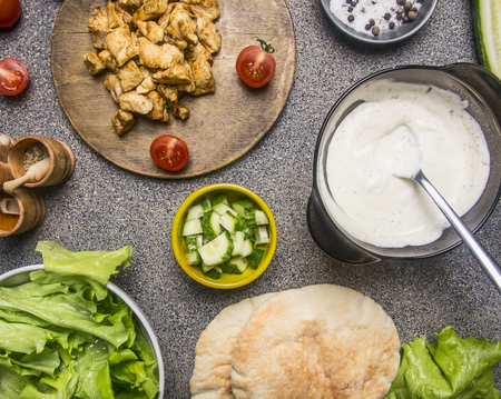 Ingredients for cooking the home doner, fried chicken, condiments, vegetables and seasonings, lined with a frame on a rustic backgroundの写真素材