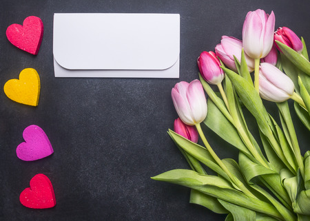 bouquet of colorful tulips and decorative hearts, lined around an envelope with congratulations, space for textの写真素材