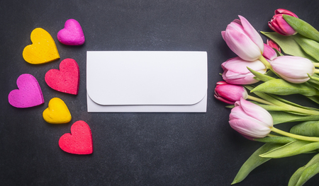 bouquet of colorful tulips and decorative hearts, lined around an envelope with congratulations, space for textの写真素材