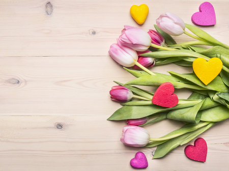 Fresh bouquet of tulips with decorative hearts as a gift for mother's day, place for text, on rustic wooden background backgroundの写真素材