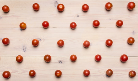 Ripe fresh cherry tomatoes lined with lines on a white wooden background, concept of vegetarian food, top viewの写真素材