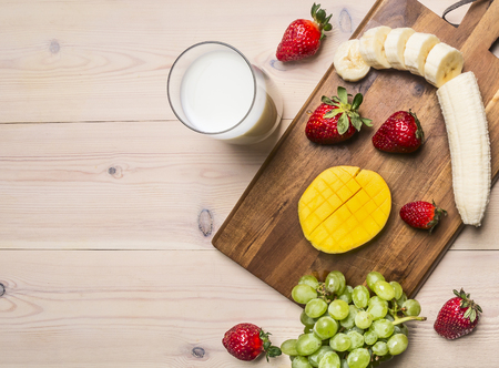 Fruits smoothies with various ingredients on white wooden background Sliced fruit lined on a cutting board,   space for textの写真素材