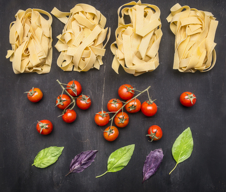 Healthy foods, cooking and vegetarian concept Raw Italian pasta with cherry tomatoes, mushrooms and butter, laid out on a rustic wooden backgroundの写真素材