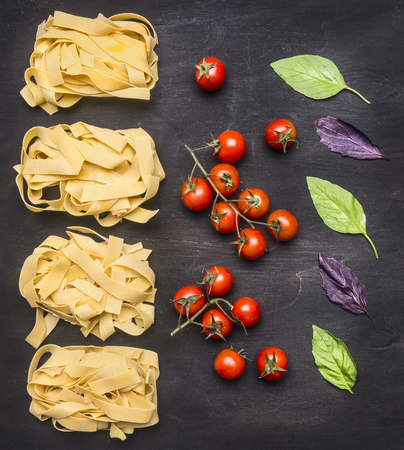 Healthy foods, cooking and vegetarian concept Raw Italian pasta with cherry tomatoes, mushrooms and butter, laid out on a rustic wooden backgroundの写真素材