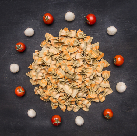 Raw Italian pasta with cherry tomatoes, mushrooms and butter, lined round on a rustic wooden backgroundの写真素材