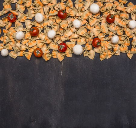 Raw Italian pasta with cherry tomatoes, mushrooms and butter, lined  on a rustic wooden background, border place for textの写真素材