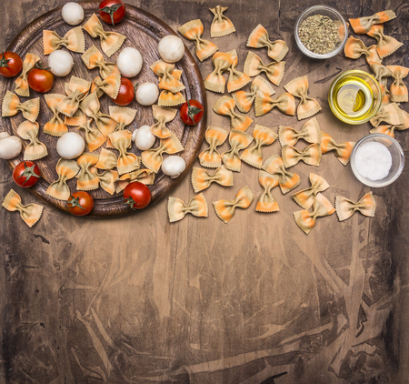 Vegetarian pasta with cherry tomatoes, herbs and seasonings, ingredients lined on a round cutting board, space for text, borderの写真素材
