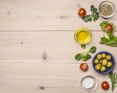 Various ingredients for the preparation of a healthy lunch, cherry tomatoes, parsley, olives and seasonings, laid out on a white rustic wooden table place for text, borderの写真素材
