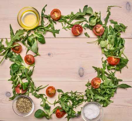 arugula and other ingredients for cooking fresh healthy salad lined with a frame on a white wooden table space for textの写真素材