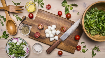 Superfoods and healthy lifestyle or detox diet food concept Preparation of salad from various fresh ingredients from arugula, cherry tomatoes, and mozzarellaの写真素材