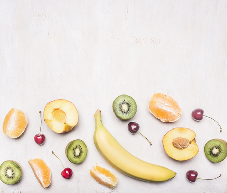Ingredients for fruit salad, kiwi, peaches, oranges, cherries, bananas, on a white wooden rustic background, border Space for textの写真素材