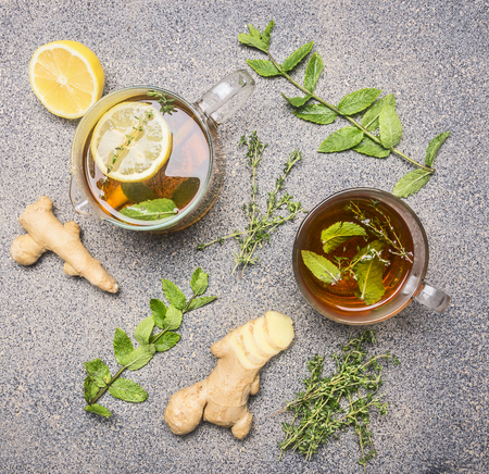 Hot tea with herbs, lemon, ginger and lemon wand, in a glass cup and teapot on a rustic granite table, top viewの写真素材