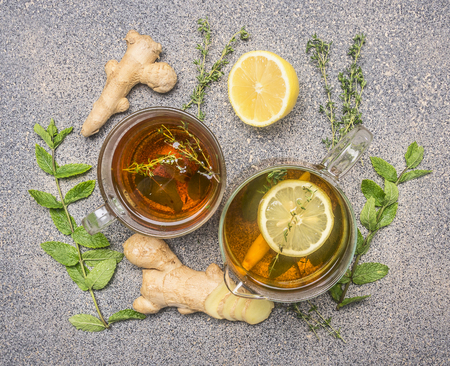 Hot tea with herbs, lemon, ginger and lemon wand, in a glass cup and teapot on a rustic granite table, top viewの写真素材
