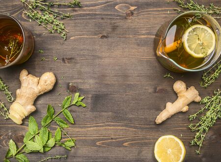 Hot aromatic tea with a root of ginger, thyme, lemon, melissa on a wooden rustic background, frame space for textの写真素材
