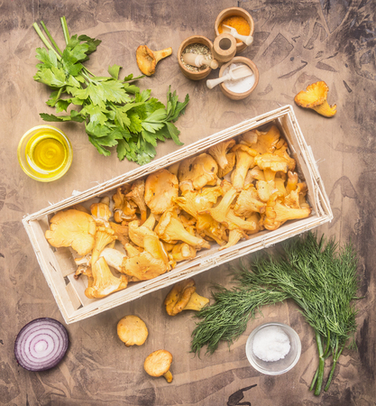 fresh raw chanterelles in a basket, with herbs and spices laid out, concept of cooking mushrooms, top viewの写真素材