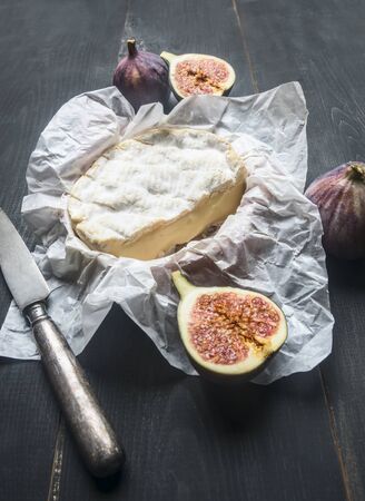 concept of appetizers for wine, camembert cheese, dark grapes, walnuts and figs, on a wooden rustic background space for textの写真素材
