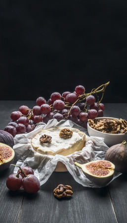 concept of appetizers for wine, camembert cheese, dark grapes, walnuts and figs with honey, on a wooden rustic background  space for textの写真素材