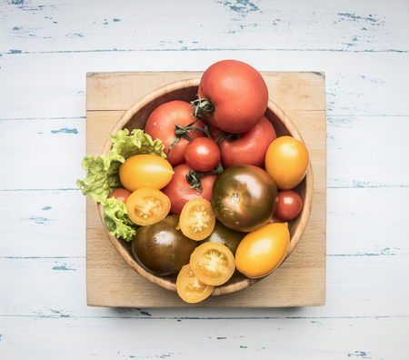 Colorful various of organic farm vegetables different varieties of tomatoes, fresh vegetables in a wooden bowl on a rustic background, top viewの写真素材