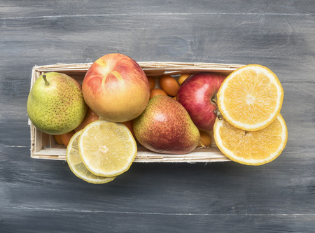 Superfoods and health or detox diet food concept variety of fruits in a wooden box  kumquat, oranges, pear, lemon, top viewの写真素材