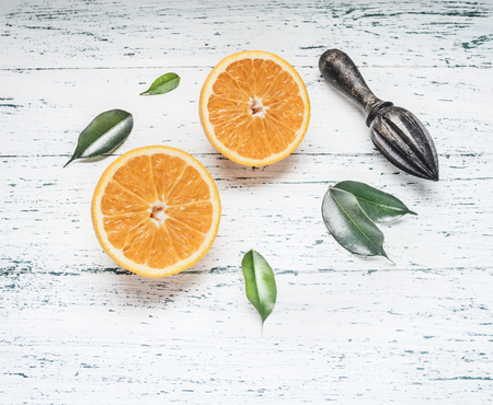 fresh sliced oranges with leaves and wooden crush for fruit, on rustic wooden background, top view, space for textの写真素材