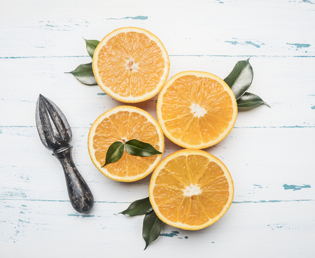 fresh sliced oranges with leaves and wooden crush for fruit, on rustic wooden background, top viewの写真素材