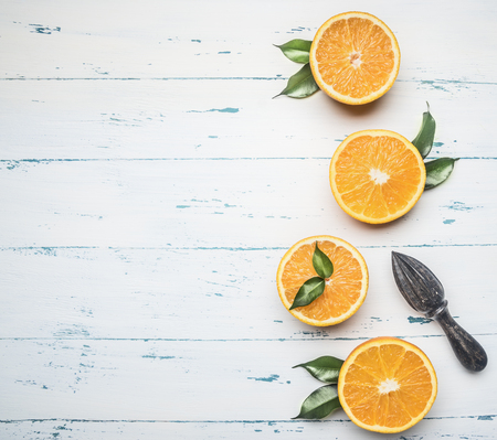 fresh sliced oranges with leaves and wooden crush for fruit, on rustic wooden background, top view, space for textの写真素材