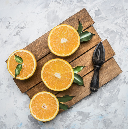 fresh cut oranges with leaves and a wooden crush for fruit, on a rustic wooden tray, top viewの写真素材