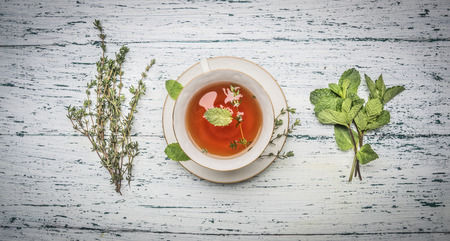 healthy autumn hot herbal tea with berries, thyme on a white wooden rustic backgroundの写真素材