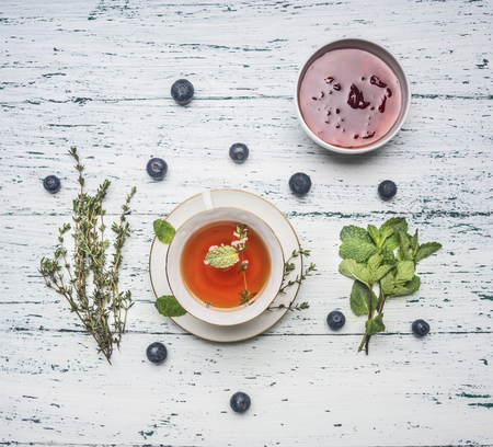 healthful autumn hot herbal tea with berries, thyme and mint, jam from a rose, a spoon, a cut lemon, on a rustic wooden background top viewの写真素材