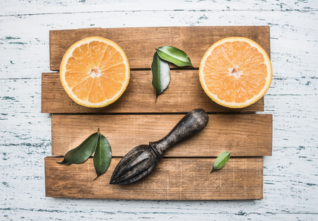 Fresh sliced orange with leaves, and a wooden crush for juice, on a wooden tray, on a white rustic background, top view, close upの写真素材